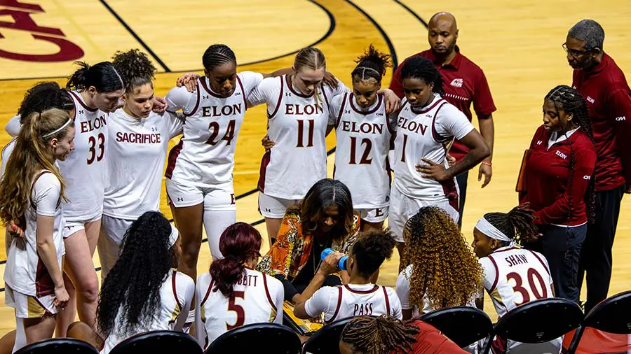 athletes in huddle with arms up